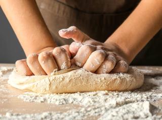 Woman kneading flour in kitchen, closeup.